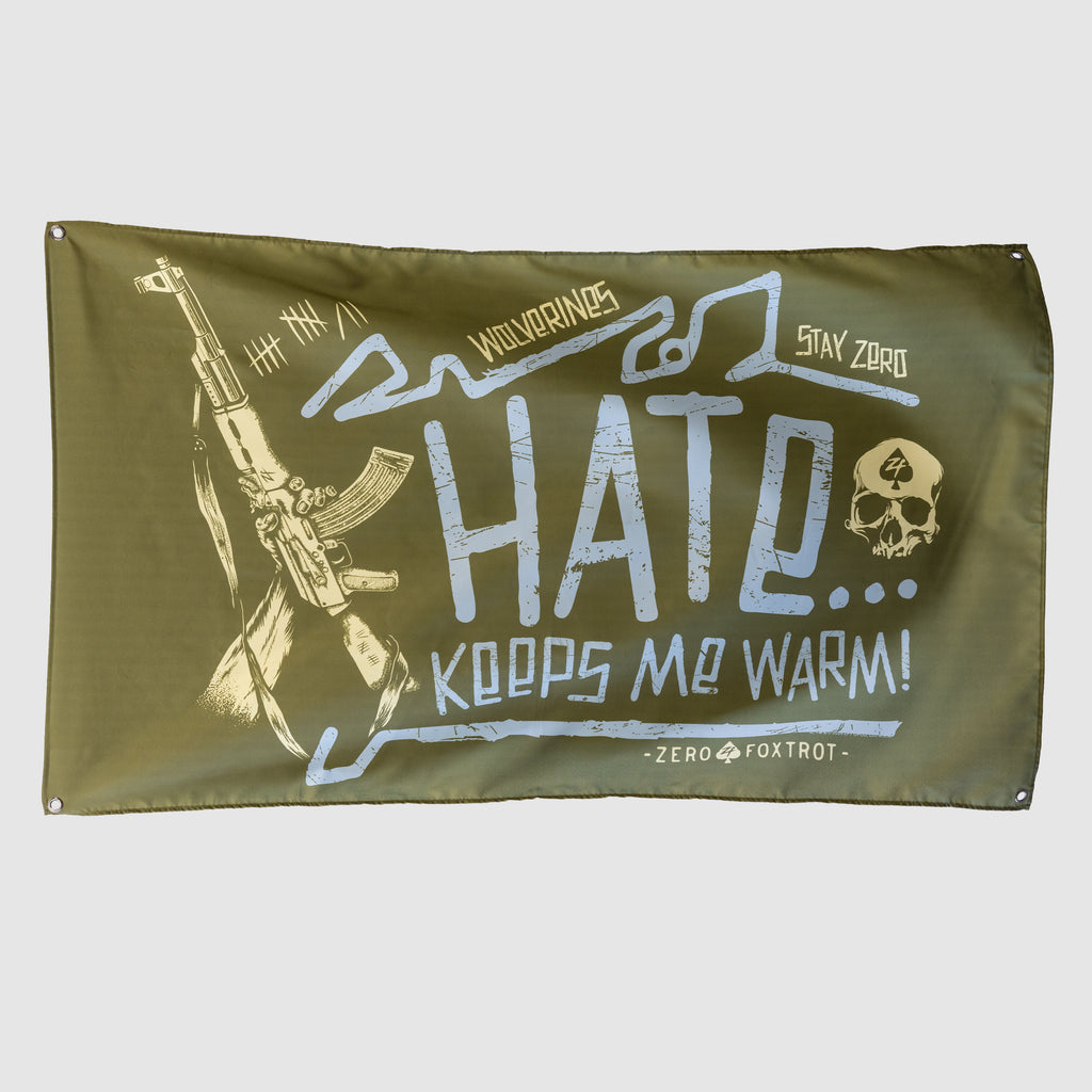 Hate Keeps Me Warm Flag in olive green with blue and cream lettering, featuring a rifle graphic, skull emblem, and distressed military inspired artwork