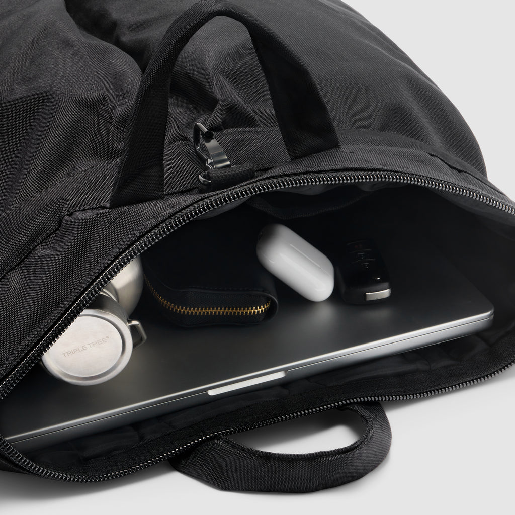 ZF Flyers Helmet Bag in black, shown open with a laptop, wireless earbuds, case, and accessories inside, featuring zippered compartments and carry handles
