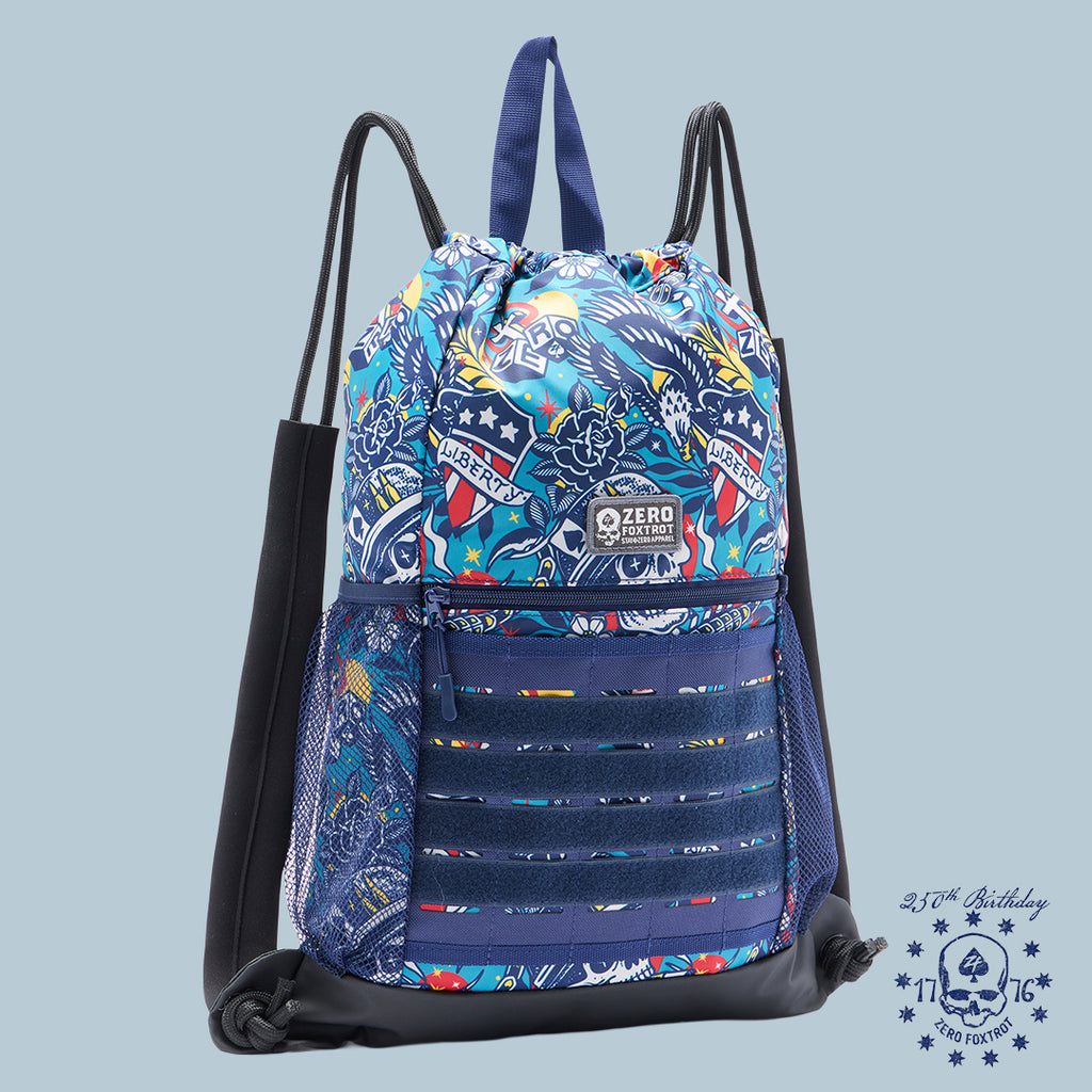 Colorful tactical drawstring pack with vibrant skull and flag designs, featuring front MOLLE-style webbing and side mesh pockets, called Liberty Skull TAC Drawstring Pack.