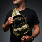 Surplus EDC Sling camouflage chest bag worn across the body with open compartments holding a handgun and gear