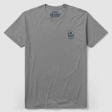 Gray crew neck t-shirt with a small dark graphic of a skull wearing a helmet with a spade symbol, displayed on the left chest area, labeled Feel the Need Tee.