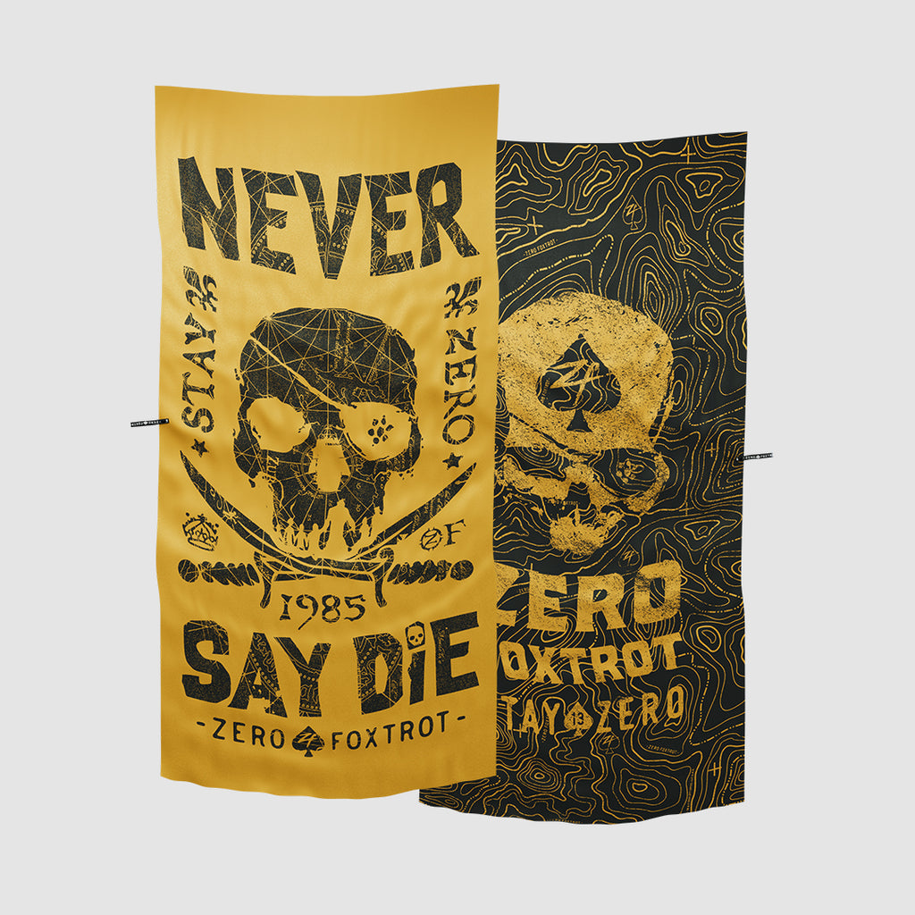 Two Microfiber Beach Towels with bold skull and text designs in black and gold colors, featuring the phrase "Never Say Die" and artistic topographic patterns.