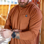 Close-up of a man wearing a rust-colored Performance Sun Hoodie with a front pocket featuring a small logo patch, adjusting his watch and showing a tattooed forearm.