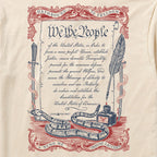 Oathbound Tee featuring a vintage-style print of the U.S. Constitution's preamble with decorative red and blue scrollwork, a coiled rattlesnake, ink bottle, quill pen, and sword on a light beige fabric.