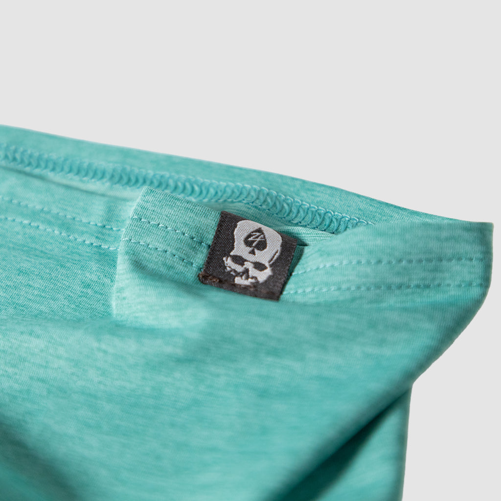Close-up of ocean blue fabric with a skull and spade logo tag on a Performance Sun Gaiter showing detailed stitching and soft material texture.