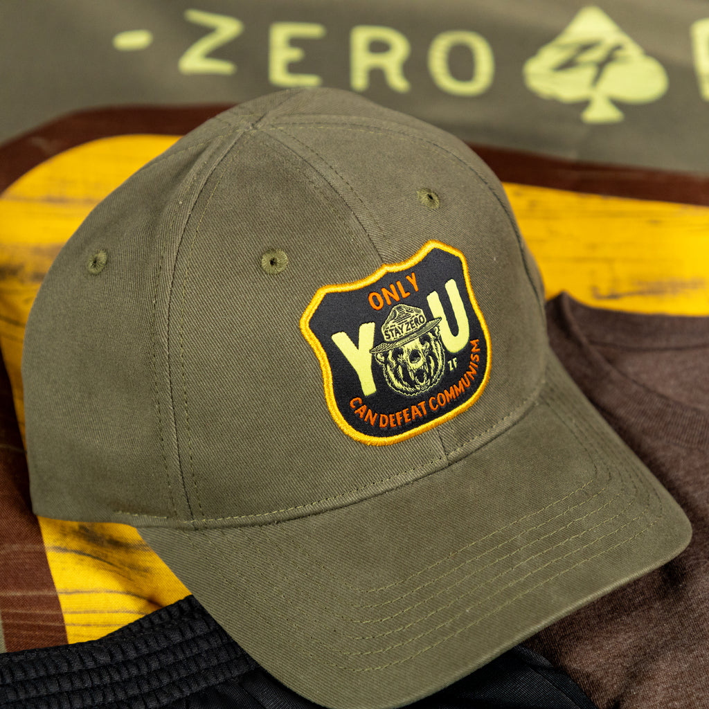 Only You Cap olive green baseball hat with curved brim and embroidered black and yellow front patch displayed on a wooden surface