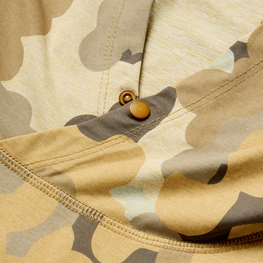 Close-up view of tan and blue camouflage fabric with a button detail on the Performance Sun Hoodie, showcasing durable stitching and textured material.
