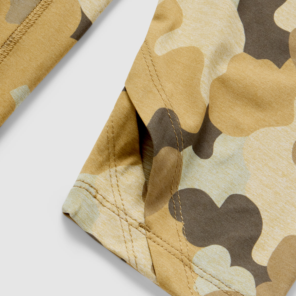 Close-up detail of tan and brown camouflage fabric with reinforced stitching on the sleeve of the Performance Sun Hoodie.