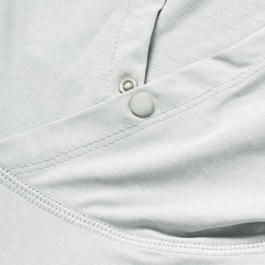Close-up detail of light gray fabric with stitching and snap button of the Performance Sun Hoodie, highlighting its smooth texture and durable construction.