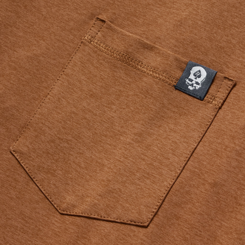 Close-up view of a rust-colored pocket detail with a small black tag on the edge, featuring the Performance Sun Hoodie.