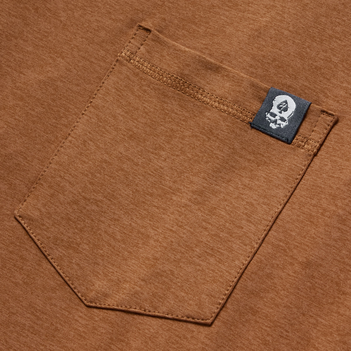 Close-up view of a rust-colored pocket detail with a small black tag on the edge, featuring the Performance Sun Hoodie.