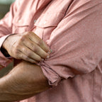Close-up of a person rolling up the sleeve of a pink textured F'n Soft Daily Shirt, highlighting the soft fabric and casual style.
