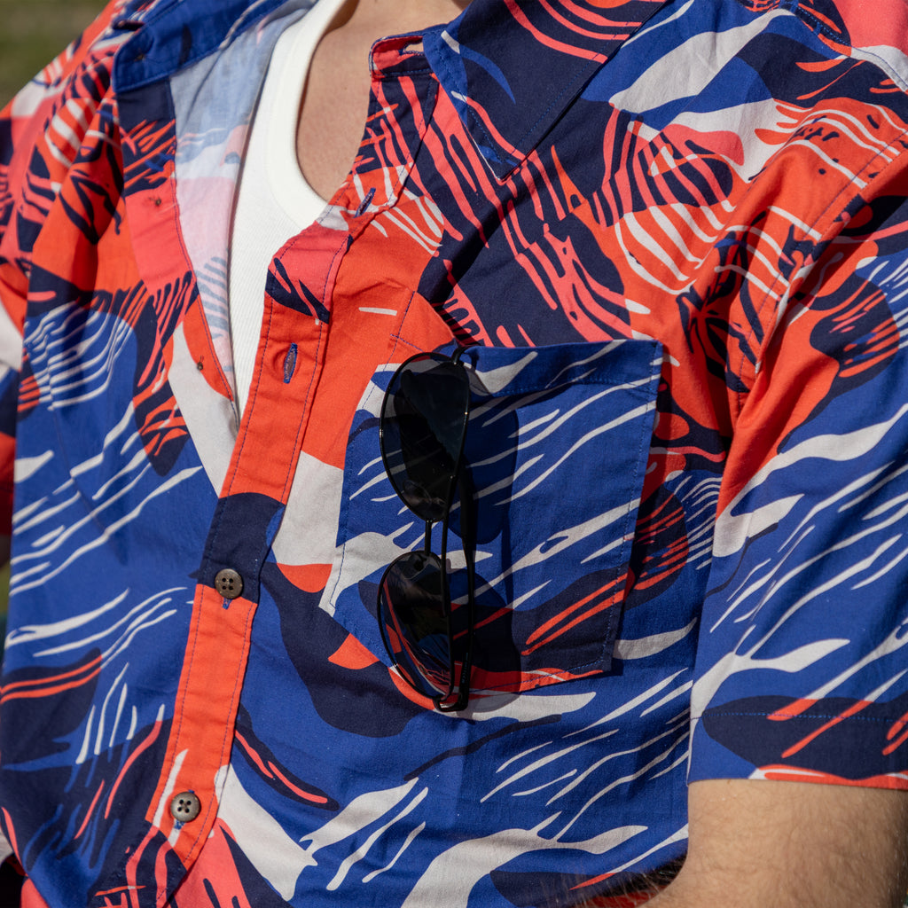 Surf Shirts (Last Chance) patterned short sleeve shirt in red, blue, and white with a button front, chest pocket, and sunglasses tucked into the pocket