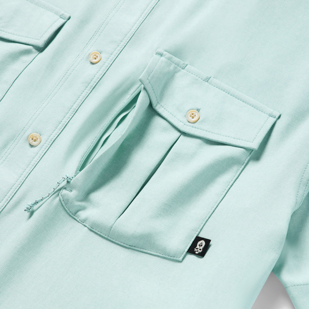 Close-up of a light aqua fabric pocket with a flap and button detail on the Short Sleeve F'n Soft Shirt, highlighting its soft texture and functional design.