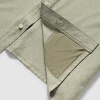 Close-up of the hem and inner pocket detail of a sage green Short Sleeve F'n Soft Shirt, showcasing the soft fabric texture and buttoned front placket.