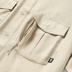 Close-up of tan fabric and detailed front pockets with button closures on the Short Sleeve F'n Soft Shirt, highlighting its soft texture and sturdy design.