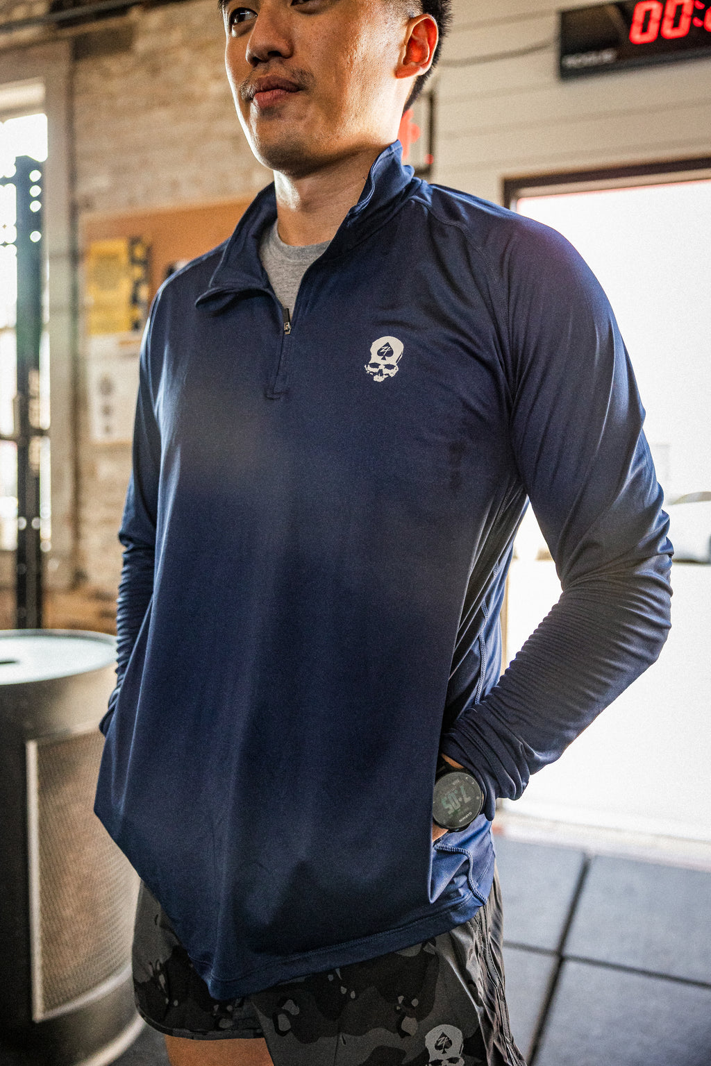 PT 1/4 Zip Long Sleeve (Last Chance) in navy with a skull logo, modeled indoors with the quarter zip collar partially open and long sleeves visible