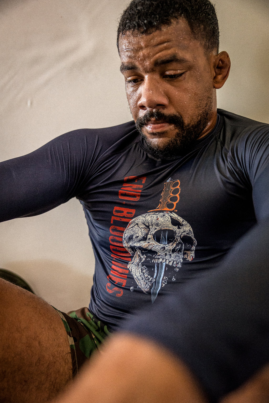 Compression Long Sleeve Rash Guard worn by a man, featuring a fitted black design with a skull graphic and red and orange lettering while he exercises.