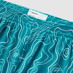 Close-up of teal Topographic Silkies shorts featuring a detailed contour line pattern and an elastic waistband with a sewn-in size label.