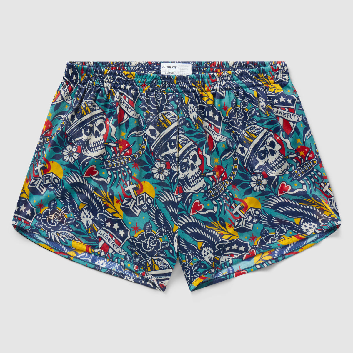 Liberty Skull Silkies boxer shorts featuring a colorful skull and floral tattoo-inspired pattern with stars, hearts, and banner motifs on a vibrant blue background.