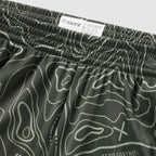 Close-up view of olive green Topographic Silkies featuring a detailed topographic contour line pattern and an elastic waistband with a branded inner label.