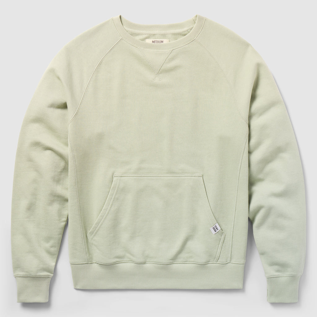 Smuggler French Terry Crew in a soft desert sage color, featuring long raglan sleeves, ribbed cuffs and hem, and a front kangaroo pocket with a small fabric tag.
