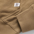 Close-up of the cuff and pocket stitching on a brown Smuggler French Terry Hoodie, featuring a small white tag with the text "STAY ZERO" for a clean, casual look.