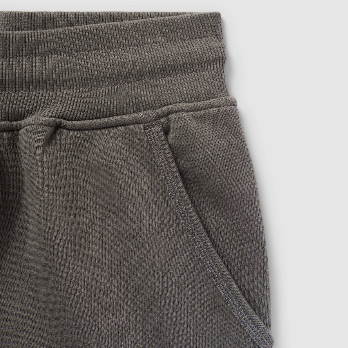 Close-up of a dark gray Smuggler French Terry Jog Shorts - 6" Inseam showing the ribbed waistband and side pocket detail in soft French terry fabric.