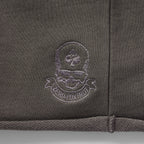 Close-up of embroidered logo detailing on dark fabric of Smuggler French Terry Jog Shorts - 6" Inseam, showcasing texture and stitching quality.