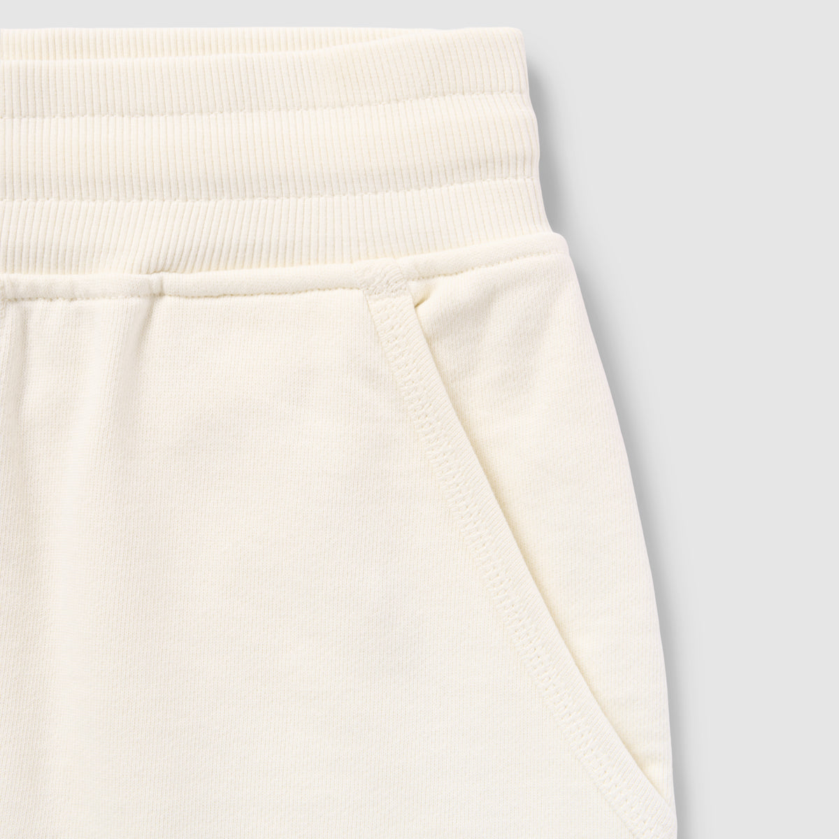 Close-up of cream-colored shorts waistband and pocket detail made from soft fabric showing texture and stitching of Smuggler French Terry Jog Shorts - 6" Inseam.
