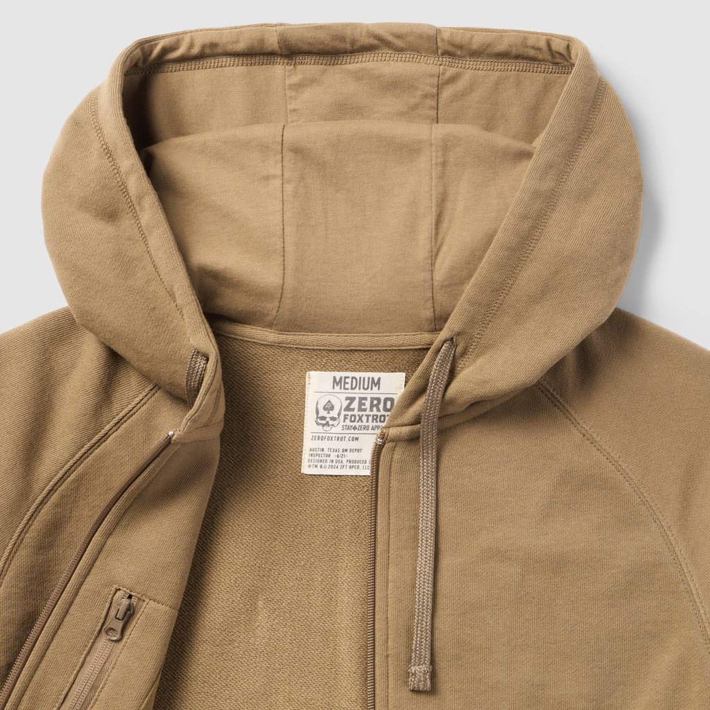 Close-up view of a tan Smuggler French Terry Zip Hoodie showing the soft textured fabric, spacious hood with adjustable drawstrings, and a partially unzipped front zipper.