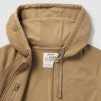 Close-up view of a tan Smuggler French Terry Zip Hoodie showing the soft textured fabric, spacious hood with adjustable drawstrings, and a partially unzipped front zipper.