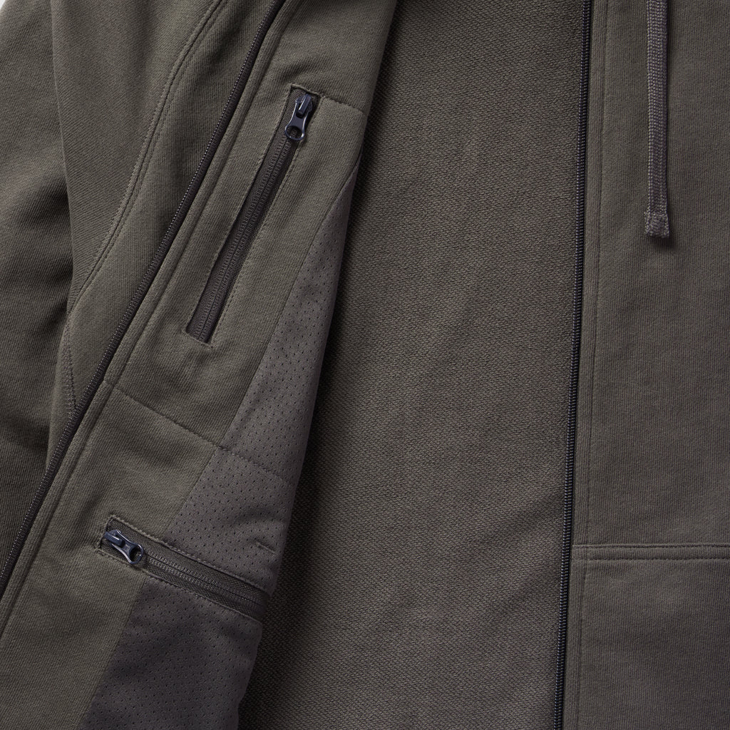 Close-up view of the interior and exterior details of the Smuggler French Terry Zip Hoodie, highlighting the zippered pockets and textured fabric in a dark, muted tone.