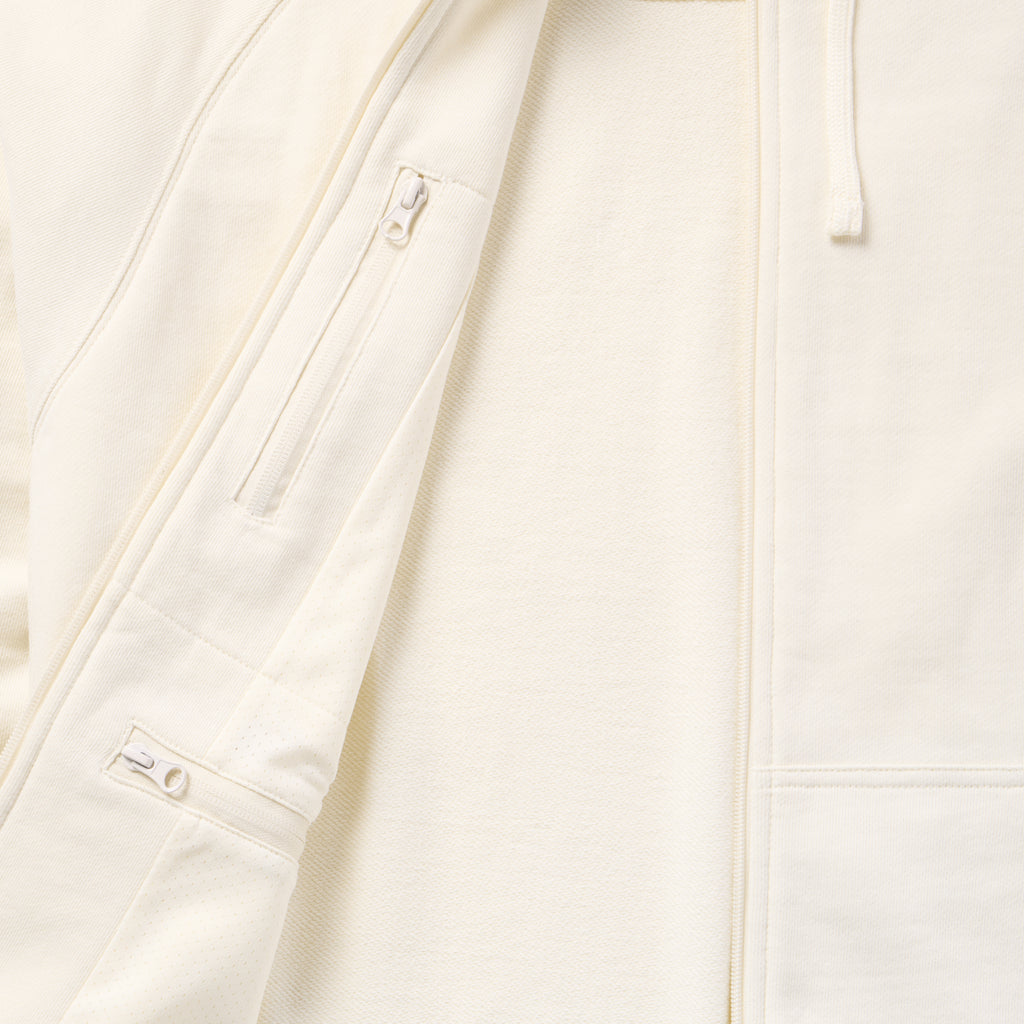 Close-up of the light-colored Smuggler French Terry Zip Hoodie showing the soft fabric texture, full front zipper, and zippered chest pocket detail.
