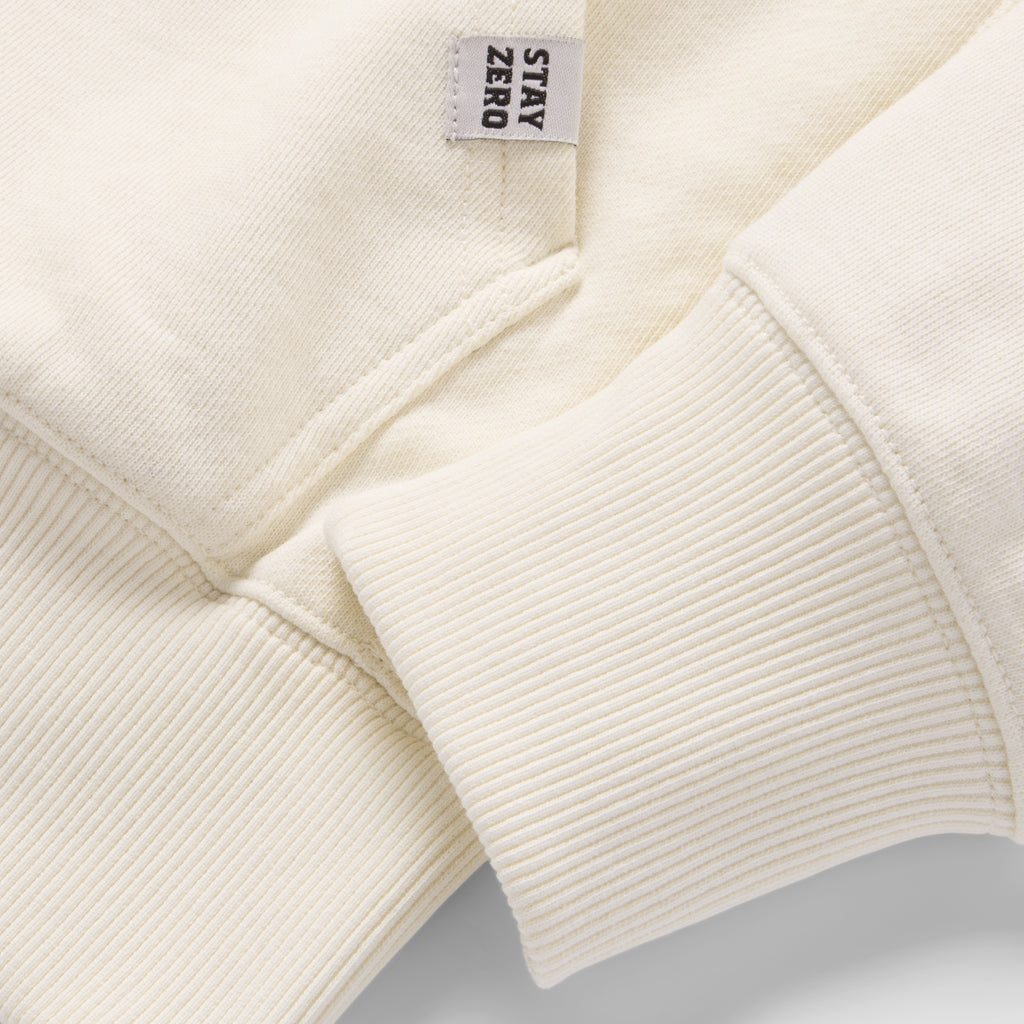 Close-up view of the off-white fabric, ribbed cuff, and small side tag on the Smuggler French Terry Zip Hoodie showcasing its soft texture and quality stitching.