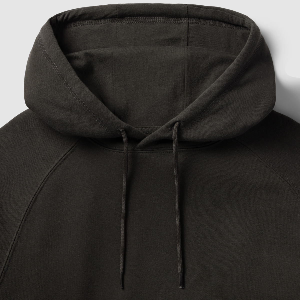 Smuggler Fleece Hoodie in black with a close up view of the hood, drawstrings, raglan seams, and soft fleece texture