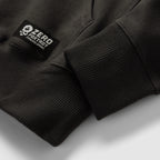 Smuggler Fleece Hoodie close-up showing black ribbed cuffs, soft fleece fabric, and a sewn sleeve label on the dark outerwear garment