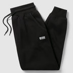 Smuggler Fleece Jogger in black with an elastic drawstring waistband, angled zip pocket, ribbed cuffs, and a small white logo on the thigh