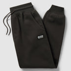 Smuggler Fleece Jogger in black laid flat, featuring an elastic drawstring waistband, side pockets, tapered legs, ribbed cuffs, and a small logo patch