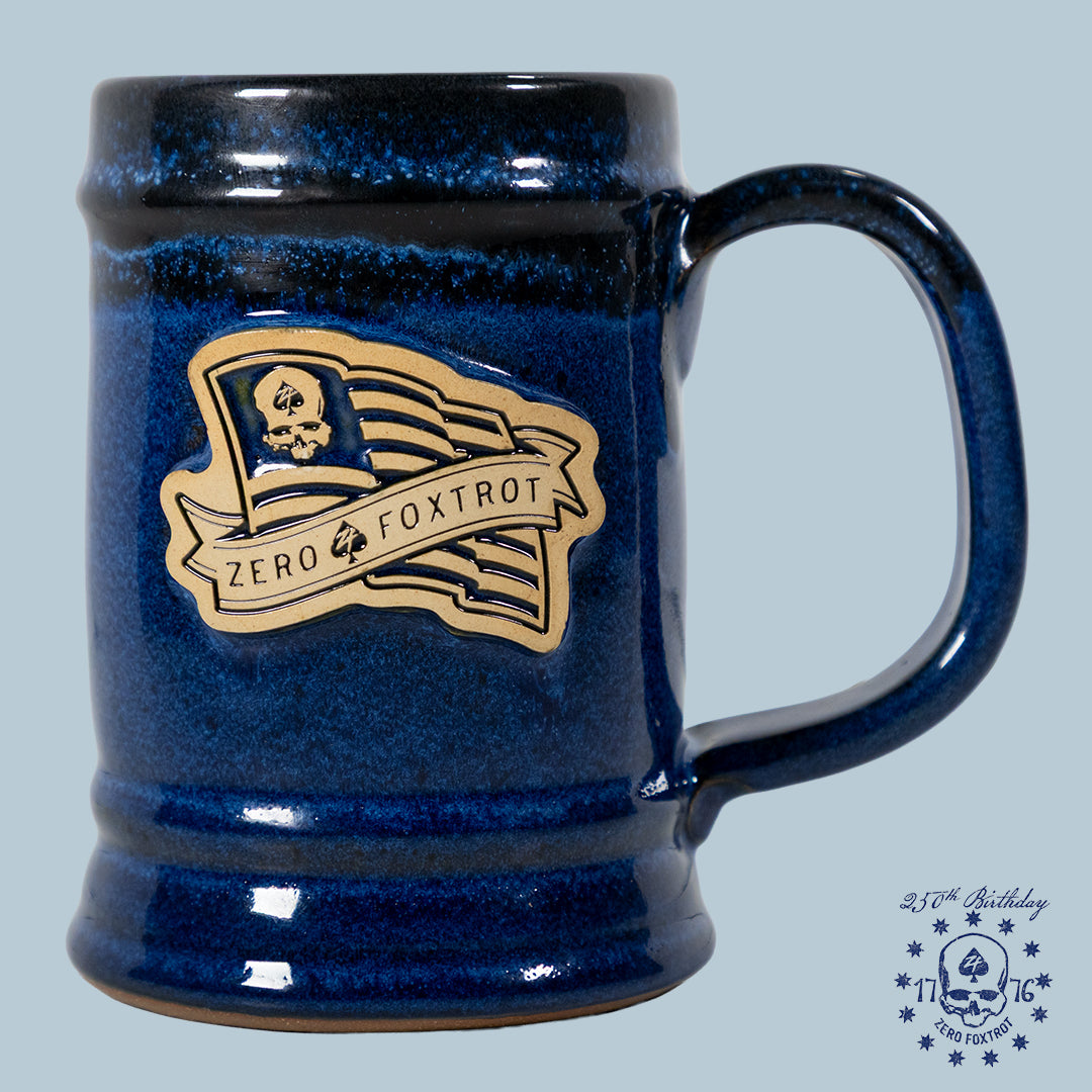 A deep blue ceramic USA Flag Stein featuring a raised emblem of a stylized skull with a flag and the words "Zero Foxtrot" on the front.
