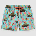 Swim Trunks featuring a light blue background with a playful pattern of vintage military tanks, jeeps, and hula dancers surrounded by pink and yellow tropical flowers and a coral drawstring waistband.
