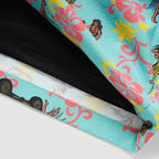 Close-up of a bright blue fabric with colorful pink and yellow floral prints and small hula dancer illustrations on Hula Tank Swim Trunks, showing detailed stitching and inner lining.