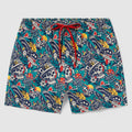 Swim Trunks with a colorful tattoo-style skull pattern featuring hats, roses, hearts, and banners on a teal background with a red drawstring waistband.