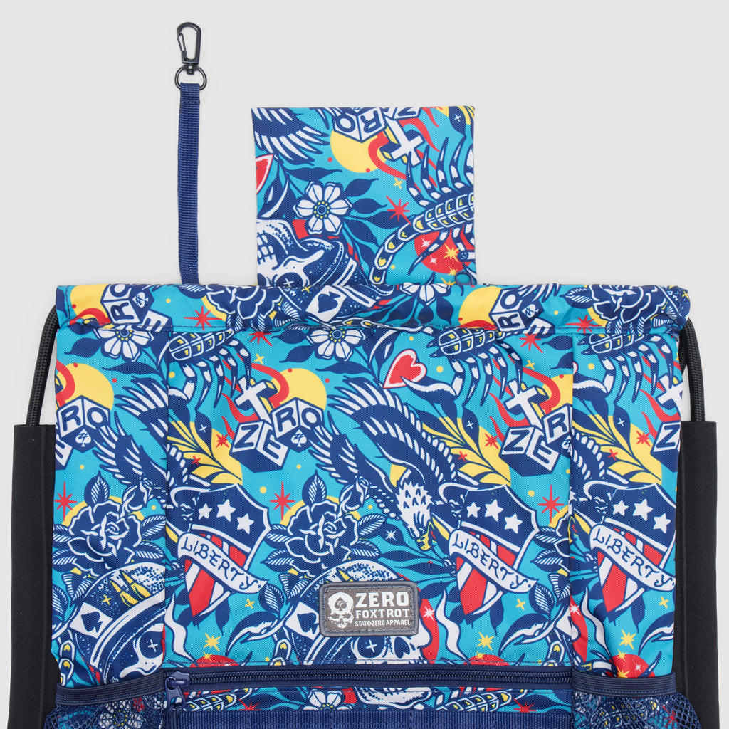 Liberty Skull TAC Drawstring Pack featuring a vibrant blue design with eagle and skull motifs, stars, and floral elements in a durable fabric with black mesh side pockets and a clip attachment.