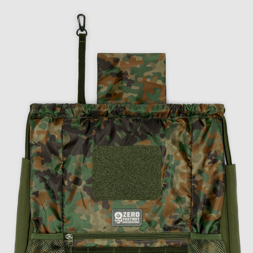 TAC Drawstring Pack in camouflage pattern featuring a top flap, front mesh pocket with zipper, and a small clip attached to a strap for secure closure or hanging.
