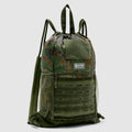 TAC Drawstring Pack in camouflage pattern featuring a drawstring closure, mesh side pockets, a front zippered compartment, and a top handle for easy carrying.