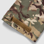 Tac Pants in camouflage fabric with a reinforced hem and adjustable strap detail close up against a light background
