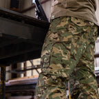Tac Pants camouflage cargo trousers with multiple utility pockets shown on a person in an industrial workshop setting