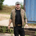 Woobie Vest (Last Chance) worn by a man, featuring a tan quilted sleeveless design layered over a black shirt with olive green sleeves in an outdoor setting