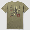 Back view of an olive green We Bred Death Tee featuring a graphic design with a bird perched on a bleeding knife, accompanied by text and symbols including "We Bred Death," "Mac V Soc," and the number 13.